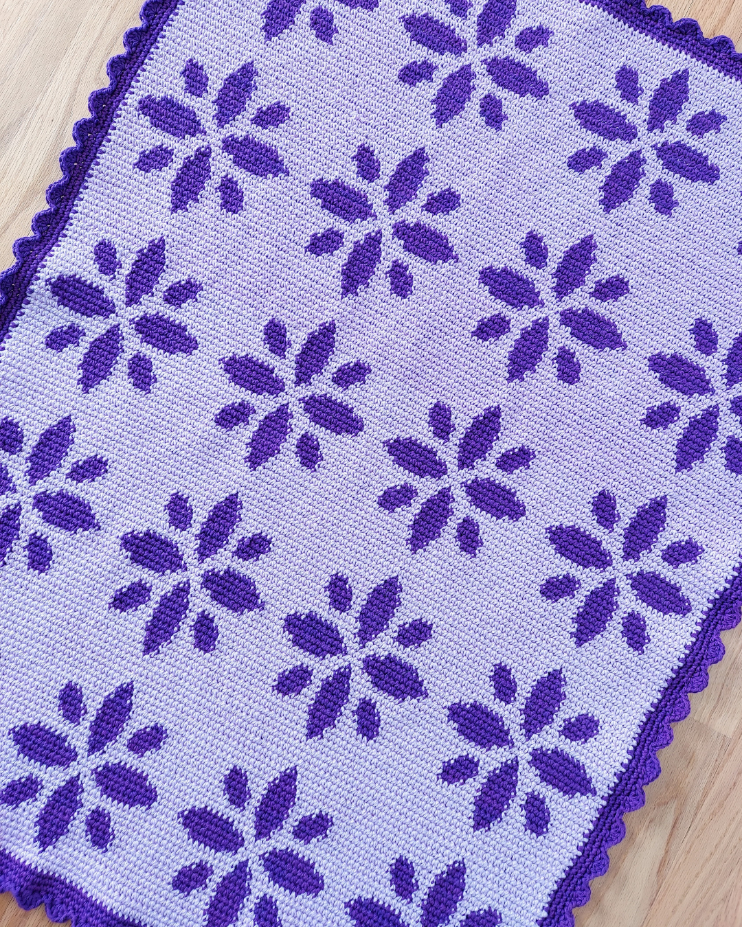 light purple blanket with dark purple flowers and dark purple scalloped trim