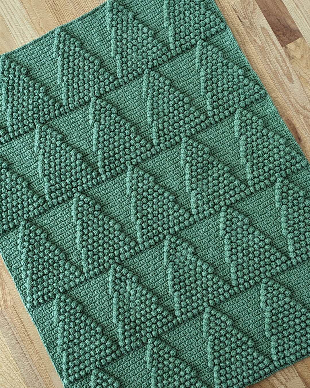 green blanket with repeating pine tree motif