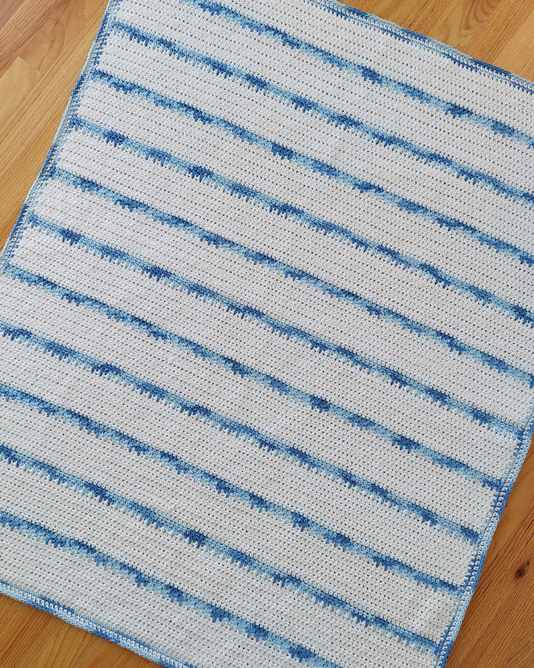 white blanket with thin variegated blue stripes and border